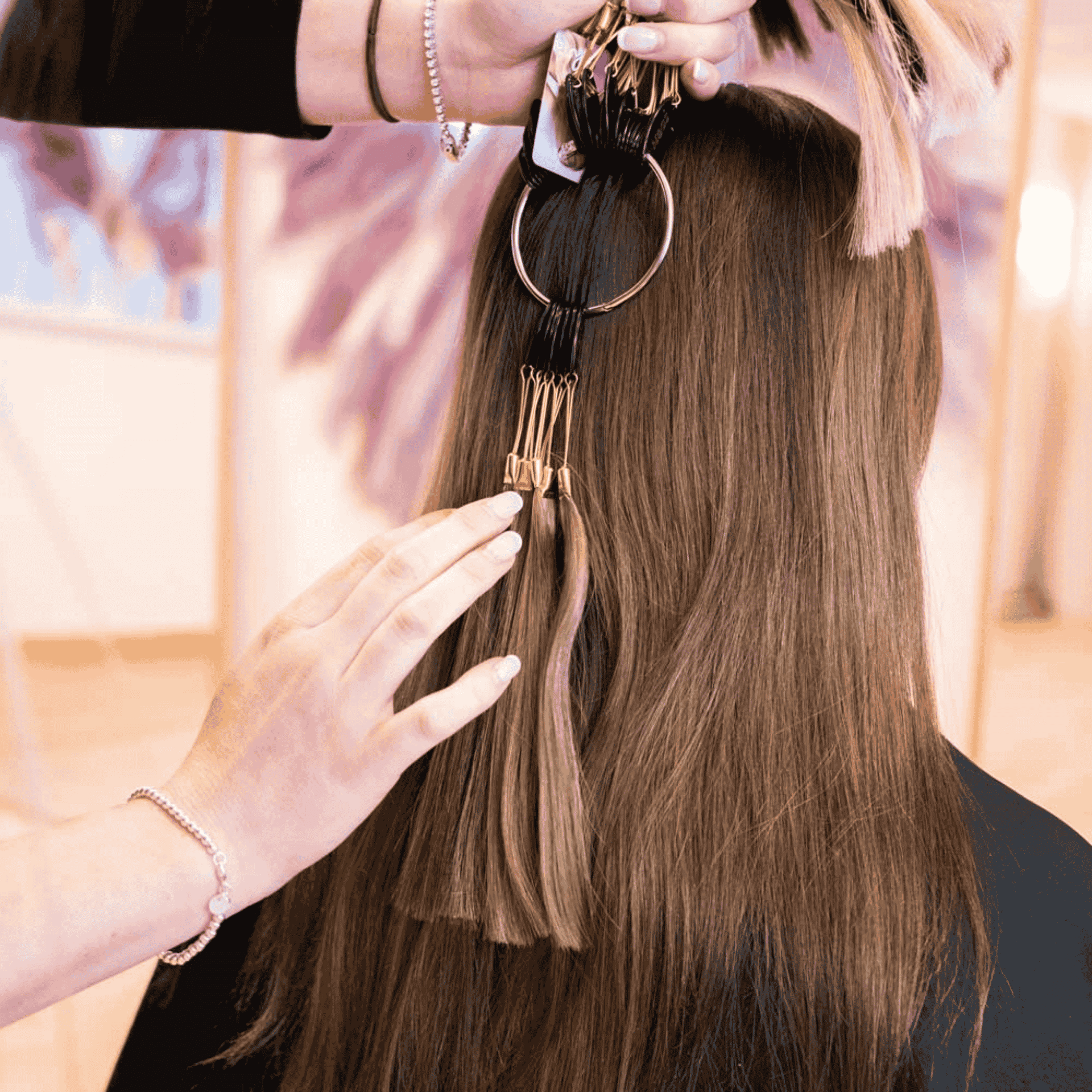 Hairstylist attaching extension to brown hair with a metal clip.